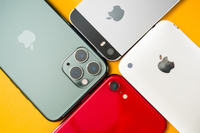 Fyra Apple mobiler i olika färger ligger mot varandra.